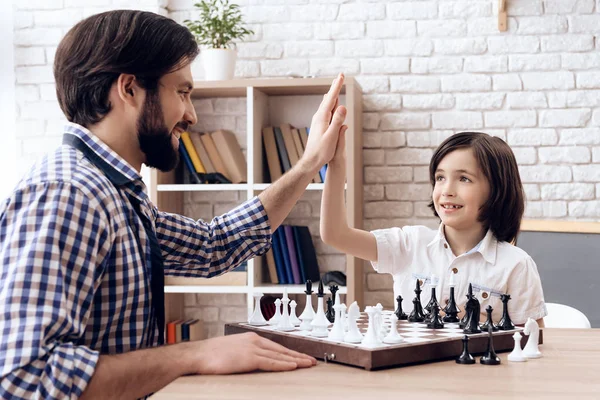 Erwachsener bärtiger Vater spielt zu Hause mit Teenager-Sohn Schach. — Stockfoto