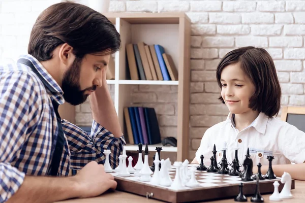 Adult bearded father plays chess with teen son at home. — Stock Photo, Image