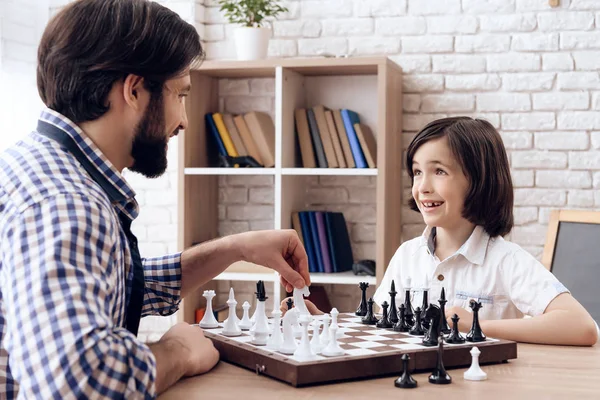 Happy bearded father plays chess with teenage son. — Stock Photo, Image