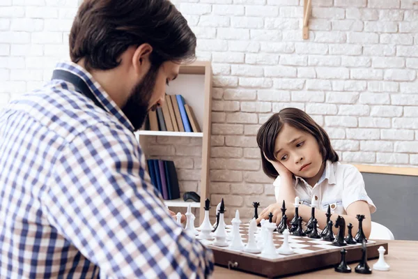 Adulte barbu père joue aux échecs avec adolescent fils à la maison . — Photo