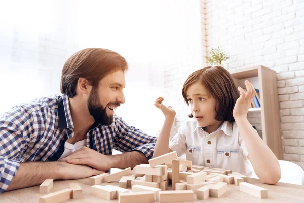 Bearded father laughs at fact that son collapsed tower Jenga of wooden blocks. — Stock Photo, Image