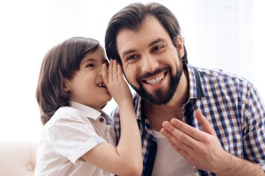 Uzun saçlı oğlu gizli kişinin kulağına bir baba söyler..