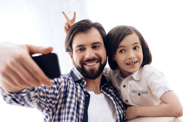 Feliz padre e hijo hacen autorretrato usando smartphone . — Foto de Stock