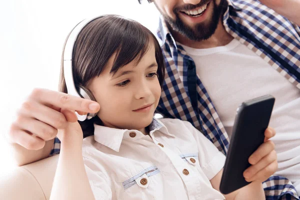 Close up. Bearded father and small son in headphones listen to music from smartphone. — Stock Photo, Image