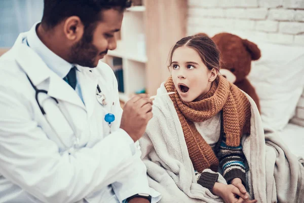 Médico indio atendiendo pacientes en casa. El doctor está examinando la garganta de una niña con frío. . — Foto de Stock