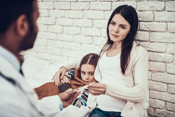 Médico indio atendiendo pacientes en casa. El médico está tomando la temperatura de la madre y la hija embarazadas . — Foto de Stock