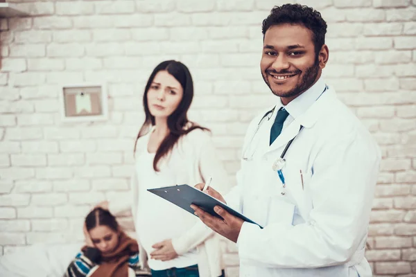 Indian doctor seeing patients at home. Pregnant mother and daughter.