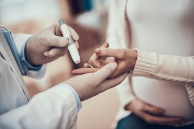 Hint doktor ofisinde hasta kabul. Doktor hamile kadının kızı ile kan şekeri ölçme.