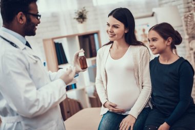 Hint doktor ofisinde hasta kabul. Doktor kızı olan hamile kadın için şurup veriyor.