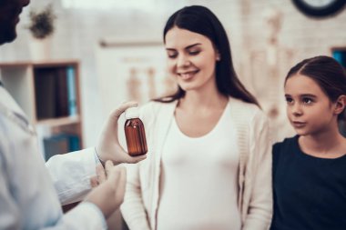 Hint doktor ofisinde hasta kabul. Doktor kızı olan hamile kadın için şurup veriyor.