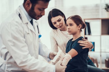 Hint doktor ofisinde hasta kabul. Doktor kızımın kolunda sargı kullanıyor.