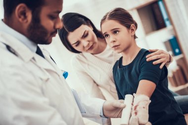 Hint doktor ofisinde hasta kabul. Doktor kızımın kolunda sargı kullanıyor.