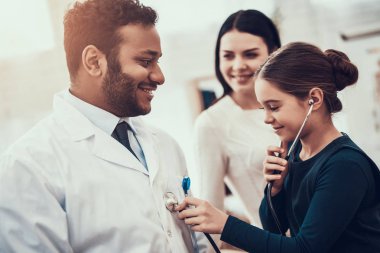 Hint doktor ofisinde hasta kabul. Kızı doktor stetoskop kullanıyor.
