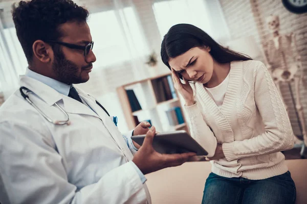 Indian doctor seeing patients in office. Doctor is showing tablet to woman.