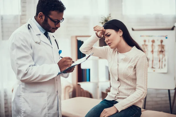 Medico indiano in visita da pazienti in ufficio. Il dottore sta ascoltando i sintomi delle donne. La donna ha la temperatura alta . — Foto Stock