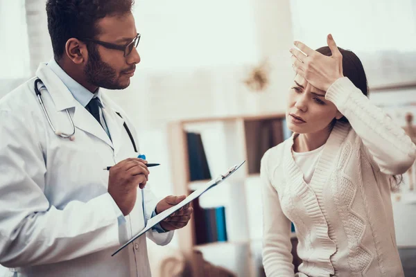 Medico indiano in visita da pazienti in ufficio. Il dottore sta ascoltando i sintomi delle donne. La donna ha la temperatura alta . — Foto Stock