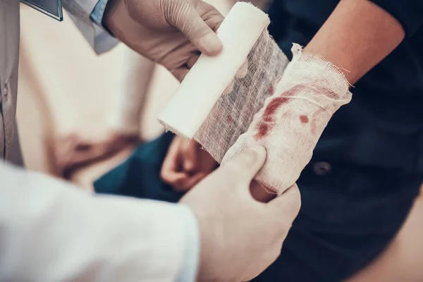 Indian doctor seeing patients in office. Doctor is using bandage on daughter's arm.