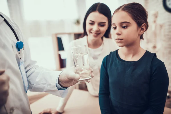 Médico indio viendo pacientes en el consultorio. El doctor le está dando pastilla y agua a su hija. . — Foto de Stock