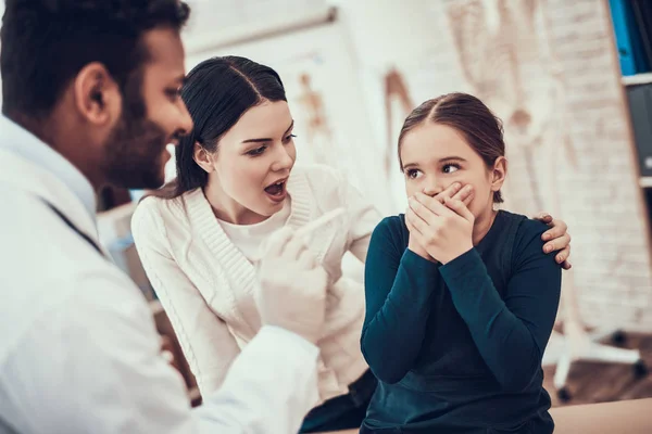 Indischer Arzt, der Patienten im Amt beobachtet. Arzt versucht, die Kehle des Mädchens zu untersuchen, aber Tochter weigert sich. — Stockfoto