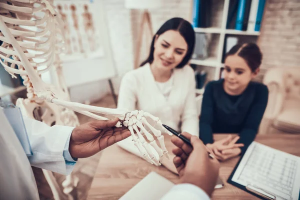 Indisk läkare ser patienter i office. Läkare visar skelett till mor och dotter. — Stockfoto