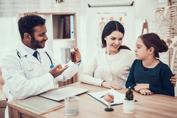 Medico indiano in visita da pazienti in ufficio. Il medico sta dando sciroppo per la tosse a madre e figlia . — Foto Stock