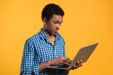 Genç Afrikalı-Amerikalı adam laptop ile çalışıyor.