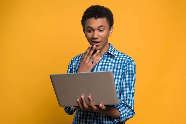 Meglepett Afro-amerikai tini néz ki a laptop képernyő. — Stock Fotó