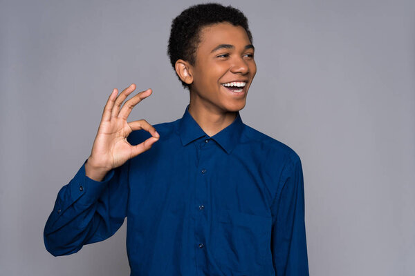 Joyful Afro American teen makes gesture ok