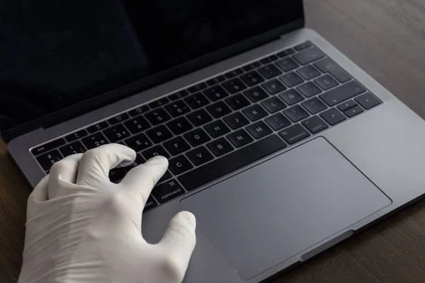 A hand writing on a computer with latex gloves