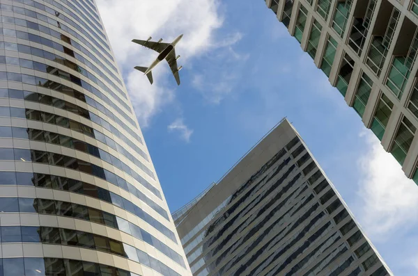 Airplane flying above  office buildings