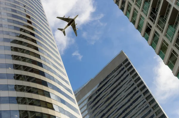 Самолет пролетает над офисными зданиями — стоковое фото