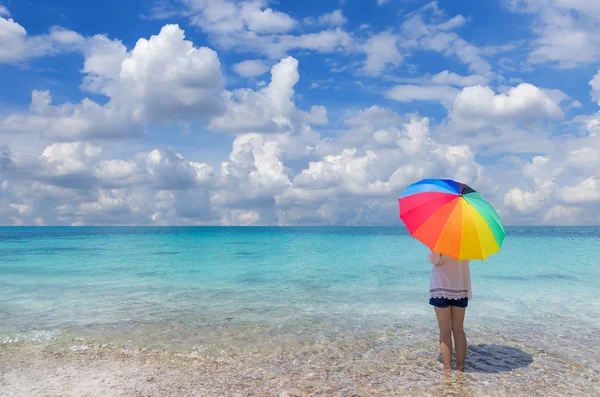 Donna con ombrellone in piedi sulla spiaggia — Foto Stock