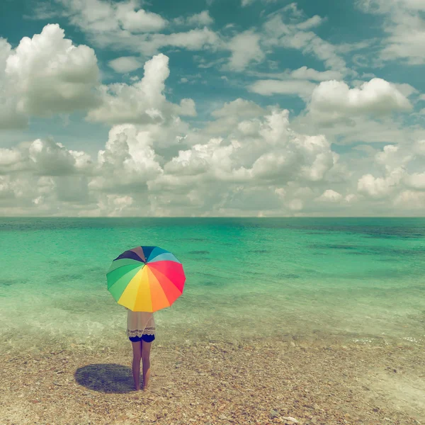 woman with umbrella standing on beach