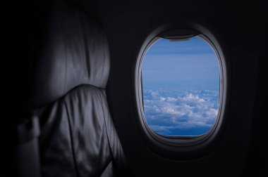 Mavi gökyüzü, seyahat ve hava taşımacılığı kavramına sahip ticari uçağın yolcu koltuğundan pencere görüntüsü.