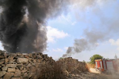 İtfaiyeciler bir araba yangınından çıkan büyük bir duman sütununu durdurmak için yoldalar.