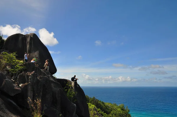 游客们坐在La Digue的大石头上 望着塞舌尔的Anse Coco — 图库照片