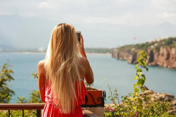 Chica turista con smartphone tomando fotos de la orilla del mar — Foto de Stock