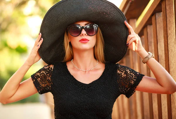 Glamorous young lady in big black hat in summer park — Stock Photo, Image
