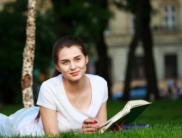 Estudante mulher pensativa em um parque da cidade lendo um livro — Fotografia de Stock