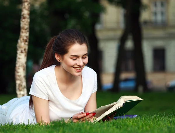 Šťastná dívka student v městském parku, čtení knihy — Stock fotografie