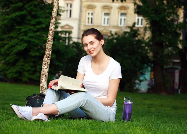 Usměvavá studentka v městském parku s knihou — Stock fotografie