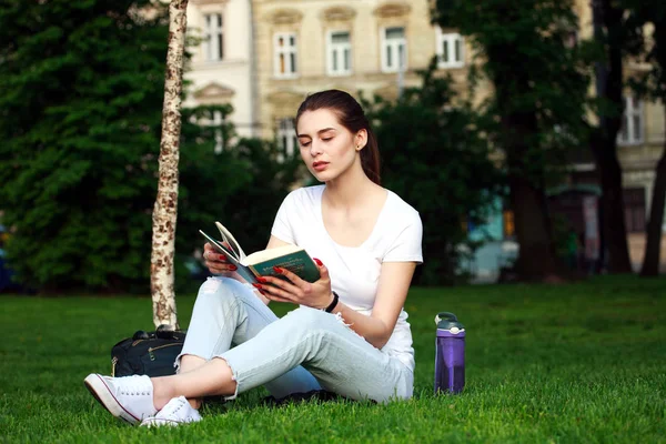 Estudiante joven en un parque de la ciudad leyendo un libro — Foto de Stock