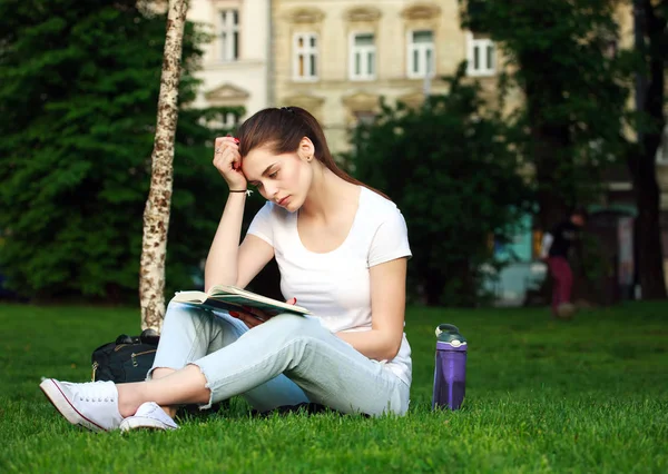 Düşünceli kadın öğrenci kitap okuma bir Şehir Parkı — Stok fotoğraf