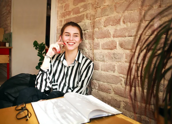 Menina feliz estudante em casa à mesa falando por telefone — Fotografia de Stock