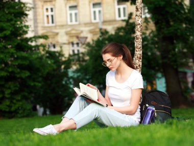 Genç kadın öğrenci kitap okuma bir Şehir Parkı 