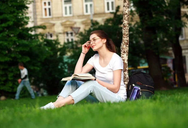 Usměvavá studentka v městském parku s knihou — Stock fotografie