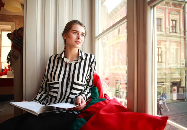 Menina estudante sentado em casa pela janela com livro — Fotografia de Stock
