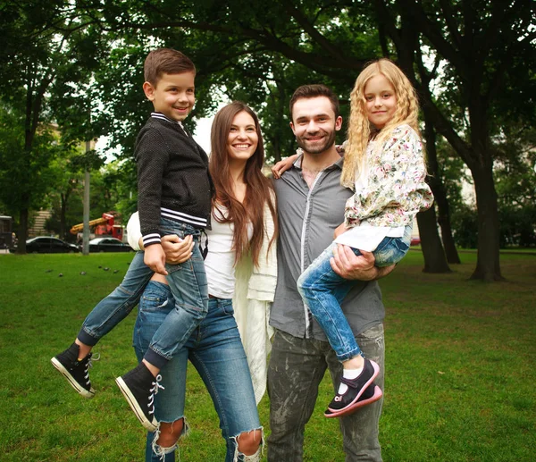 Giovane famiglia felice con due bambini nel parco verde estivo — Foto Stock