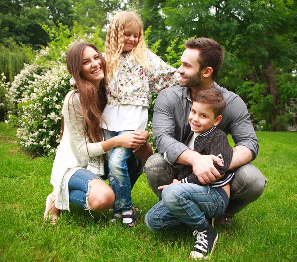 Jonge gelukkig gezin met twee kinderen in de zomer groen park — Stockfoto