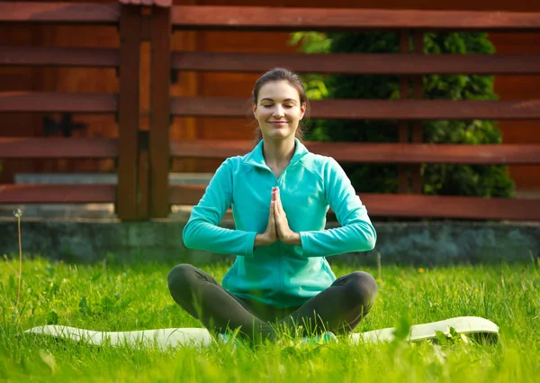 Jonge vrouw in zomer park doen yoga met gesloten ogen — Stockfoto